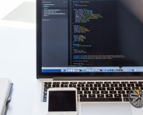 A macbook pro with a phone and notepad